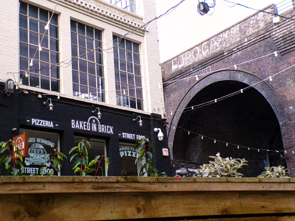 baked in brick - a pizza place in the custard factory. there is a tunnel arch behind it with fairy lights hanging 